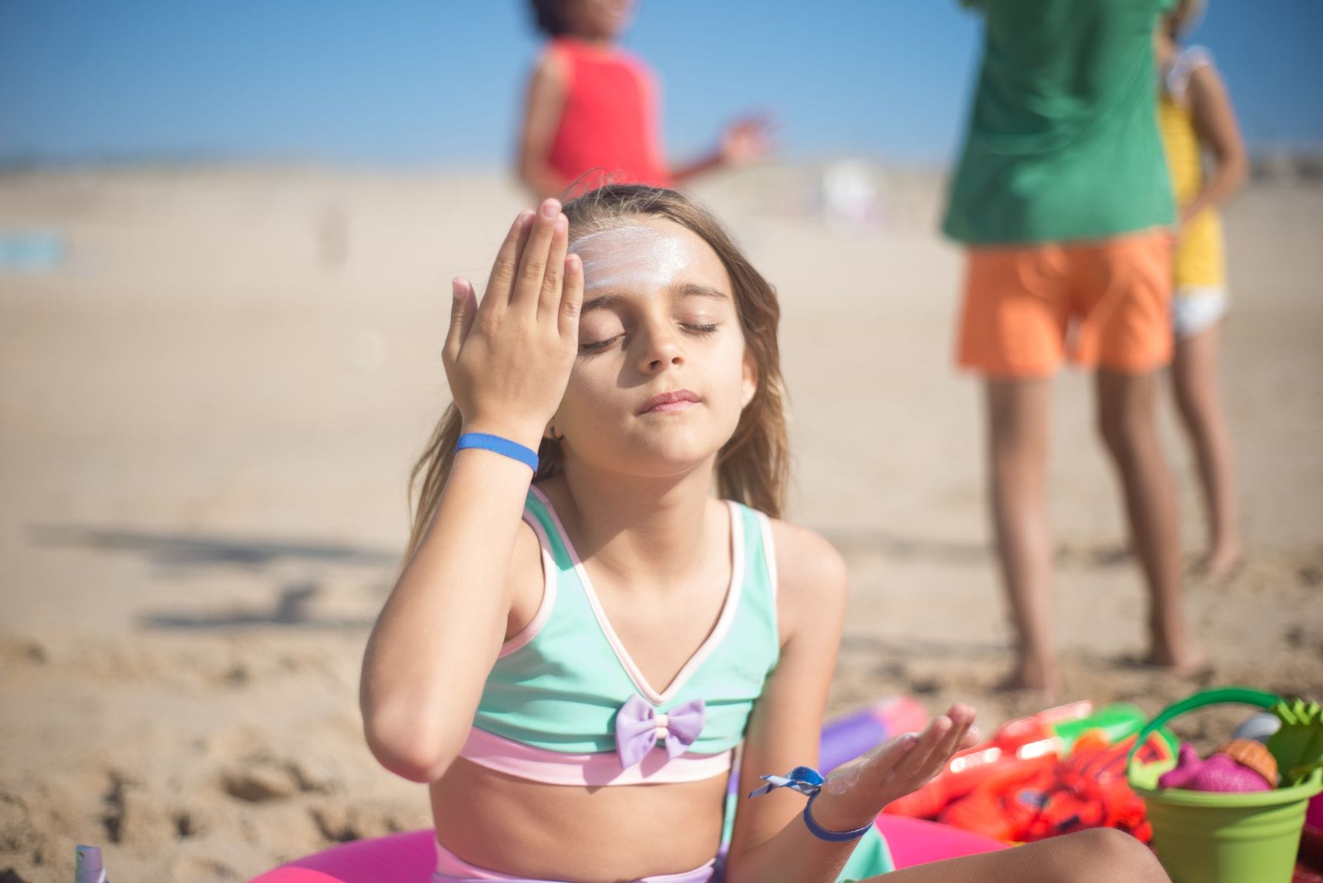 Dziewczyna nakłada krem z filtrem na plaży w słoneczny dzień