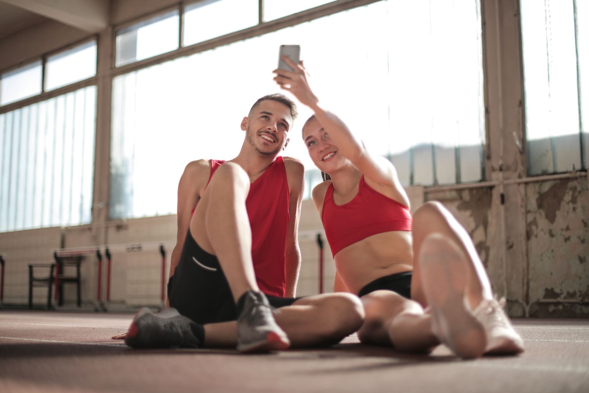 Para po treningu na podłodze siłowni robiąca selfie