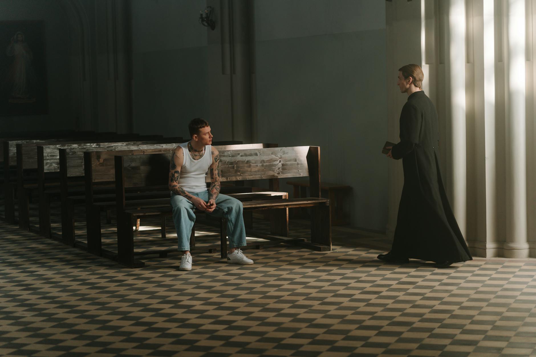 Wytatuowany mężczyzna rozmawia z księdzem w ławce kościoła