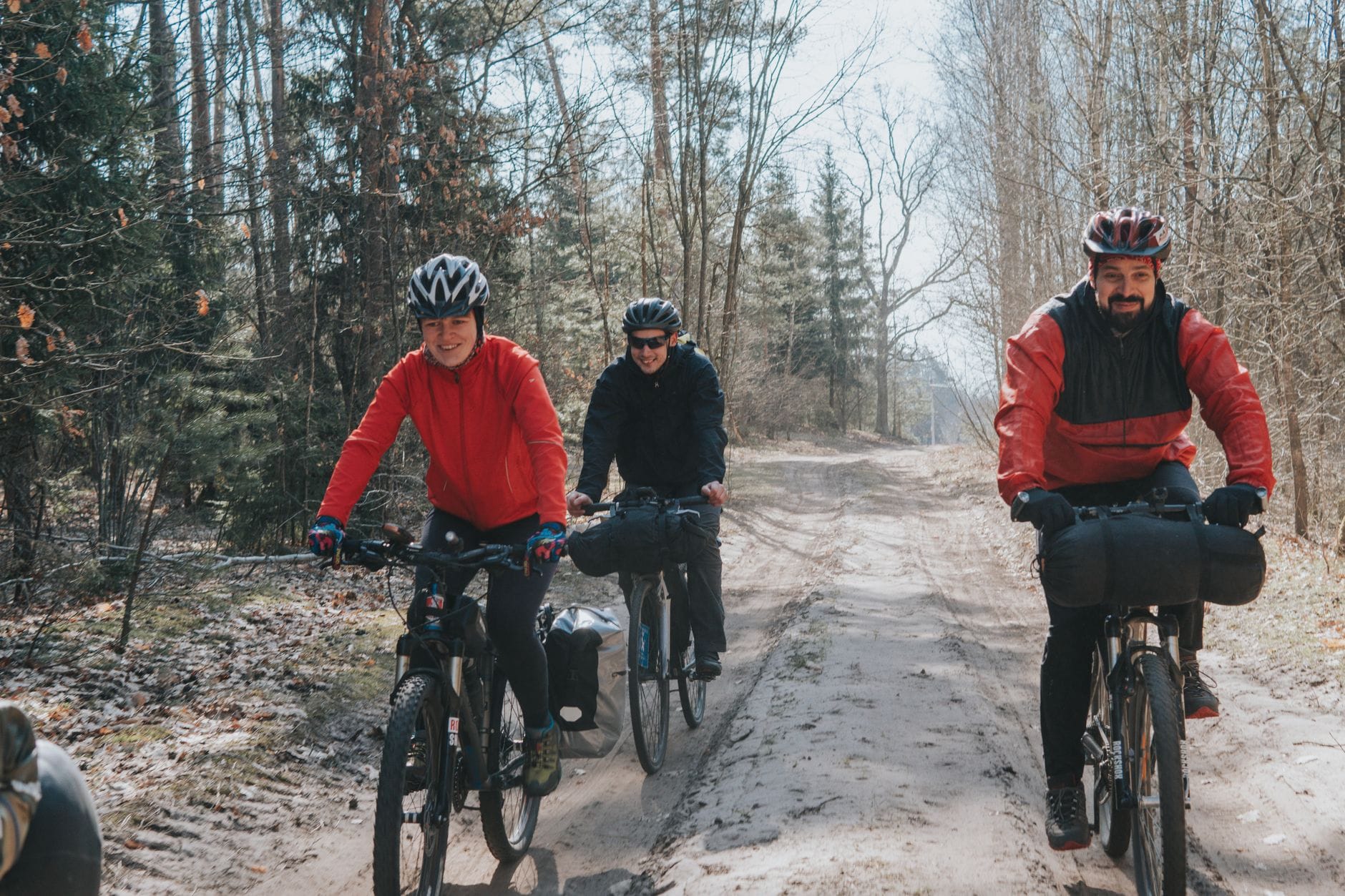 Trzech rowerzystów jedzie leśną ścieżką podczas wyprawy bikepackingowej