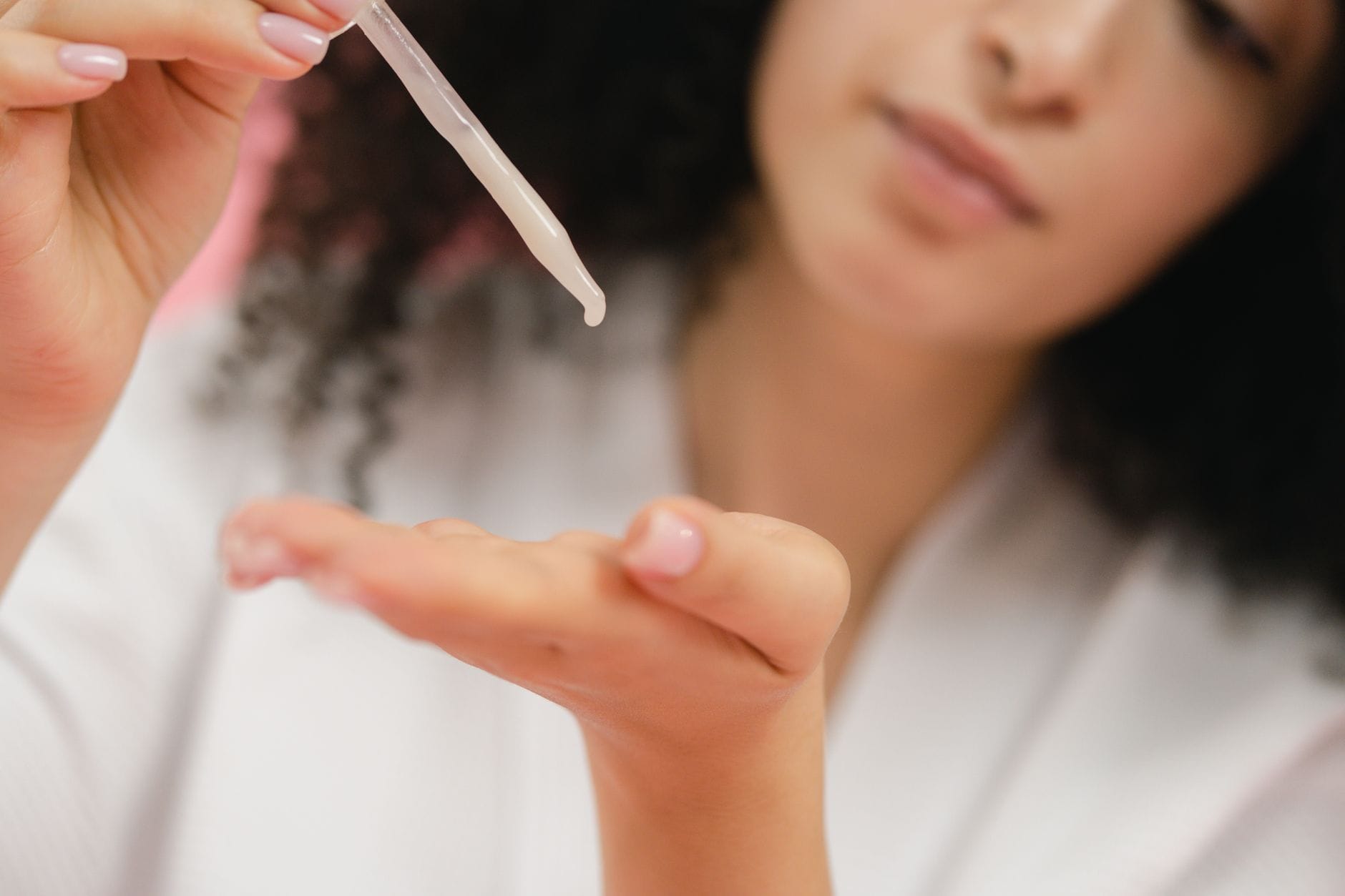 Kobieta z pipetą nakłada serum pielęgnacyjne na skórę